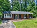 Charming brick ranch with manicured lawn and black shutters, set against a backdrop of lush trees at 1356 Lori Ct, Conley, GA 30288