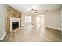 Spacious living room with a stone fireplace, ceiling fan, and wood grain flooring at 1577 Keystone Dr, Conley, GA 30288