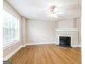 Bright living room featuring beautiful floors, a cozy fireplace, ceiling fan, and ample natural light at 182 Spivey Glen Dr, Jonesboro, GA 30236