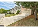 Suburban home featuring a long driveway and two-car garage, surrounded by green lawns and trees at 737 Shadow Lake Dr, Lithonia, GA 30058
