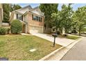 Suburban home with a well-manicured lawn, a two-car garage, and mature trees providing shade at 737 Shadow Lake Dr, Lithonia, GA 30058