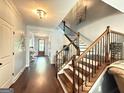 Grand foyer with dark wood floors, an elegant chandelier, and a beautiful staircase with iron spindles at 8340 Nolandwood Ln, Villa Rica, GA 30180