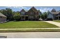 Two-story home with stone facade, a lawn, and a long driveway with multiple cars at 8340 Nolandwood Ln, Villa Rica, GA 30180