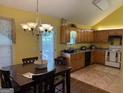Eat-in kitchen featuring natural wood cabinets, tile floors, vaulted ceiling and view of the back yard at 1432 Eagles Nest Cir, Carrollton, GA 30116