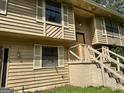 Close-up of a two-story home's exterior, featuring wood siding, shutters, and front stairs needing some repair at 4079 Day S Trl, Ellenwood, GA 30294