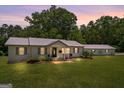 Charming single-story home at dusk featuring a metal roof, neutral siding, well-manicured lawn, and detached garage at 204 First St, Bowdon, GA 30108