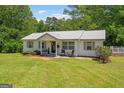 Charming single-story home with manicured lawn, metal roof and inviting front porch with seating at 204 First St, Bowdon, GA 30108