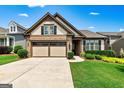 Charming home with a two-car garage, stone accents, and well-manicured landscaping on a sunny day at 123 Mulberry Ct, Peachtree City, GA 30269