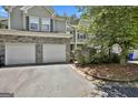Charming townhome featuring a two-car garage with stone accents, mature landscaping, and neutral siding at 508 Las Brasis Ct, Peachtree City, GA 30269