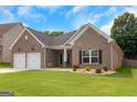 Charming brick home featuring a manicured lawn and a two-car garage, under a bright blue sky at 1243 Polk Xing, Mcdonough, GA 30252