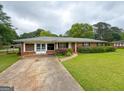 Lovely brick home featuring a well-maintained lawn, mature trees, and a concrete driveway at 5141 Hiram Lithia Springs Rd, Powder Springs, GA 30127
