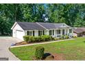 View of white brick home with black shutters, attached garage and long driveway at 3210 Roseheath Ln, Lithonia, GA 30038
