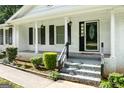 Charming covered front porch featuring white brick, black shutters, black front door and stairs at 3210 Roseheath Ln, Lithonia, GA 30038