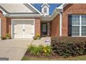 Close-up of a brick home with an inviting entrance, colorful flowers, and a two-car garage at 395 Sylvan Loop, Fayetteville, GA 30214