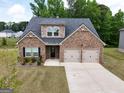 Aerial view of a brick home with a two-car garage, showcases the driveway and surrounding landscaping at 1225 Hibiscus Way, Mcdonough, GA 30253