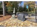 Stone patio featuring an outdoor dining set, grill, and privacy fence, surrounded by mature trees at 2119 Pine Heights Ne Dr, Atlanta, GA 30324