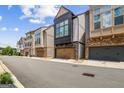 Street view of the townhome, showing attached garage and stacked stone and neutral colored siding at 1058 Kirkland Cir, Smyrna, GA 30080