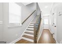 Bright foyer with hardwood floors, stairs with wood and iron railing, white walls, and entry door at 1058 Kirkland Cir, Smyrna, GA 30080