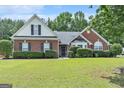 Charming red brick home with lush green lawn and manicured hedges under a blue sky at 1108 The By Way, Mcdonough, GA 30252