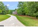 Long driveway leads to a lovely two-story home surrounded by mature trees and a lush green lawn at 220 Drumcliff Ct, Tyrone, GA 30290