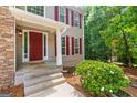 Close-up of the home's entry with a red door, white trim, and green bushes at 220 Drumcliff Ct, Tyrone, GA 30290