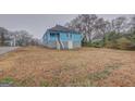 Exterior view of a blue home featuring a large, empty yard and a side door with a screened-in porch at 1730 Spring Ne St, Conyers, GA 30012