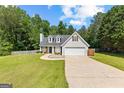 Beautiful home showcasing a manicured lawn, gray siding, and a spacious two-car garage at 75 Mcintosh Estates Ct, Sharpsburg, GA 30277