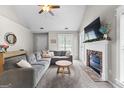 Bright living room featuring a cozy fireplace, vaulted ceilings, and a large sectional sofa at 75 Mcintosh Estates Ct, Sharpsburg, GA 30277
