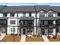 View of the townhome exteriors showing the front porches, black accents, and a street lamp at 823 Mackay Crk, Woodstock, GA 30188
