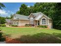 Attractive home featuring a lush green lawn, well-maintained landscaping, and a combination of stone and stucco facade at 115 Blue Grass Way, Oxford, GA 30054