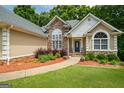 Charming single-story home featuring a stone facade, manicured landscaping, and an inviting entrance at 115 Blue Grass Way, Oxford, GA 30054