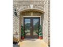 Elegant front door with decorative glass, flanked by potted plants, welcomes you to this beautiful home at 1516 Winward Dr, Locust Grove, GA 30248