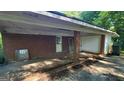 Brick carport featuring a door and ample covered space for vehicle storage with overhead lighting at 1417 Lake Cir, Mableton, GA 30126