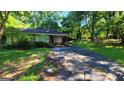 A ranch style home with a brick exterior and a carport surrounded by trees and an overgrown lawn at 1417 Lake Cir, Mableton, GA 30126