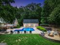 Backyard view of a sparkling blue pool, a brick pool house, a cozy firepit and green, landscaped surroundings at 704 Branchview Ct, Mcdonough, GA 30252