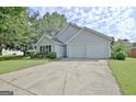 View of the gray home showing the driveway, lush lawn, and attached two-car garage at 10690 Tara Village Way, Joneboro, GA 30238