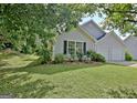 Landscaped front yard with lush green grass and mature trees surrounding the gray home at 10690 Tara Village Way, Joneboro, GA 30238