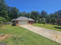 Long driveway leading to a single-story brick home surrounded by lush greenery and mature trees at 212 Hunting Court, Jonesboro, GA 30236