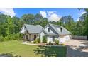 Beautiful white farmhouse with an attached garage, lush landscaping, and a welcoming front porch, nestled amongst mature trees at 11807 Alcovy Rd, Covington, GA 30014