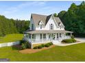 Inviting two-story home featuring a wraparound porch and lush landscaping at 692 Brooks Woolsey Rd, Brooks, GA 30205