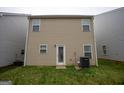 Rear exterior of home with tan siding, symmetrical windows, a glass door, and small grassy backyard at 1579 Leonard St, Hampton, GA 30228