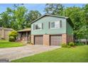 Split level house with a brick facade, two car garage, and mature trees at 7455 Dover Ct, Riverdale, GA 30274