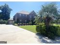 A stately brick home with manicured lawn and mature trees; driveway leads to attached garage at 1869 Schofield Dr, Hampton, GA 30228