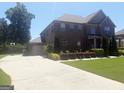 Two-story brick home with attached garage and a long driveway, set on a well-maintained lawn at 1869 Schofield Dr, Hampton, GA 30228