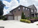 Brick home featuring a spacious driveway and three-car garage and professional landscaping that adds to its charm at 1869 Schofield Dr, Hampton, GA 30228