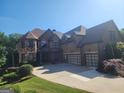 A large brick home with a three-car garage and a well-manicured lawn at 4818 Moon Hollow Ct, Buford, GA 30519