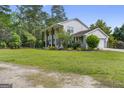 View of white home with two-car garage, green lawn and mature trees at 75 Auburn Rd, Auburn, GA 30011