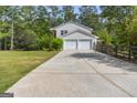 Long driveway leading to a two-car garage on a white house, with a wooden fence and lush greenery at 75 Auburn Rd, Auburn, GA 30011