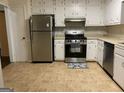 Functional kitchen equipped with stainless steel appliances, white cabinetry, and neutral tile flooring at 1725 Sara Se Ct, Conyers, GA 30013