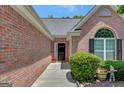 Charming brick home entrance with a black door, complemented by well-maintained landscaping and decorative elements at 85 Parks Pl, Sharpsburg, GA 30277